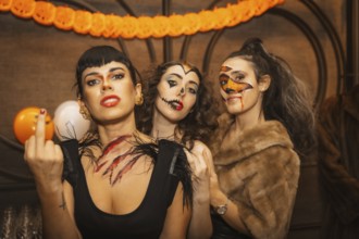 Female friends in costumes at halloween party with friends in disco nightclub, looking at camera