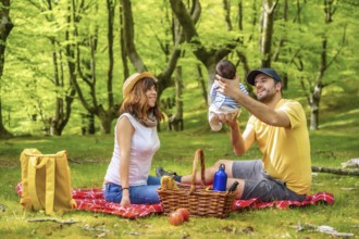 A family on a picnic day with their newborn son. Dressed in a white and yellow t-shirt