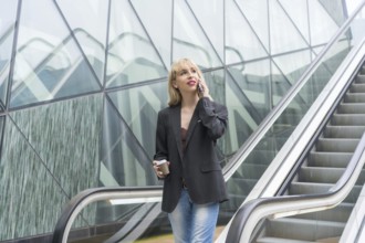 Entrepreneurial girl in business park in a modern building with escalator, young blonde in a suit