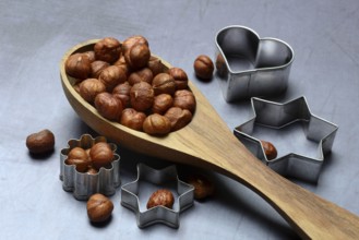 Wooden ladle with hazelnuts, cookie cutters, baking ingredient