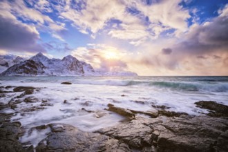 Beach of Norwegian sea on rocky coast in fjord on sunset in winter. Vareid beach, Lofoten islands,