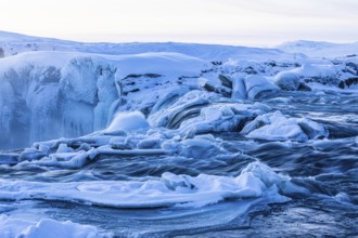 Icefall at the edge of the Godafoss waterfall at dawn, snow-covered landscape, Northern Iceland