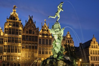 Antwerp famous Brabo statue and fountain on Grote Markt square illuminated at night and old houses.