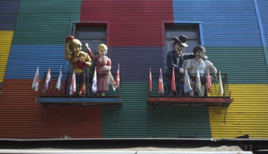 Colourful house facades with balconies and figures, decorated with flags, La Boca district, Buenos