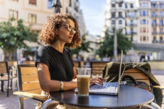 Side view of a beauty confident arab businesswoman working with laptop and drinking coffee outdoors