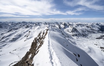 Tracks in the snow on a narrow mountain ridge in winter, summit of Piz Grialetsch, view of mountain