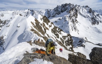 Mountaineer belaying on a steep snow slope, belaying on a rope, ascent to the summit of Piz