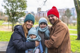 Smiling family bundled in warm winter clothes, enjoying a cheerful day outdoors in a city park,