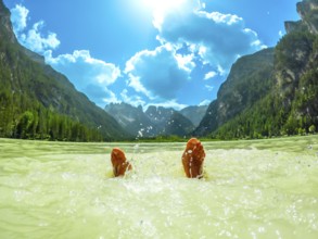 Feet splashing in the water of a mountain lake in the italian dolomites during summer, with a