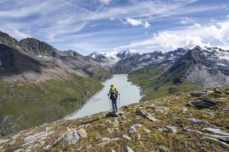 Mountaineer on the summit of Mont de la Blana, view of a blue mountain lake, Lac des Dix reservoir,