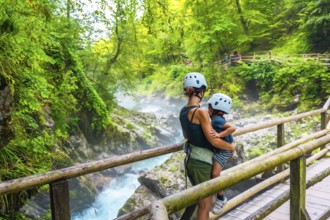 Mother holding her child while admiring the stunning vintgar gorge near bled, slovenia, during