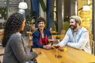 Multiracial male and females friends talking and drinking beer at bar outside roof at night