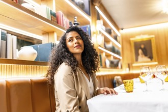 Side view photo of a beauty chic latin woman sitting distracted in a restaurant looking aside alone