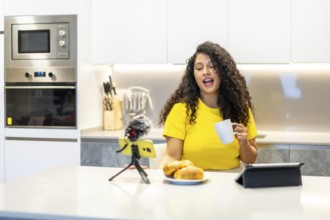 Female latin young and beauty content creator streaming online while having breakfast at home