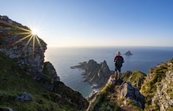 Mountaineer on the summit of Måtind or Måtinden, view of picturesque coastal landscape with sun