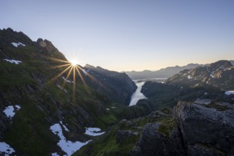 Picturesque mountain landscape at sunrise with sun star, fjord Trollfjord and Raftsund, hike to