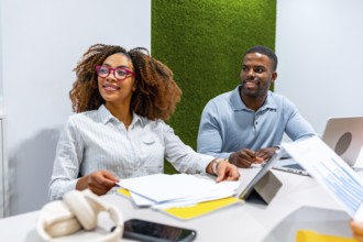 Two managers are cooperating in a modern coworking office, analyzing financial reports and