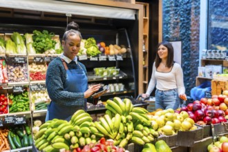 Grocery store employee using a digital tablet for inventory management of fresh fruits and