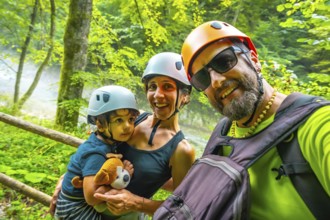 Smiling family wearing helmets taking a selfie while hiking in the beautiful vintgar gorge near