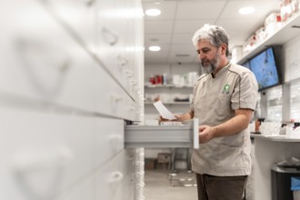 Side view of a male mature pharmacist looking for medicines in the storage room of a store