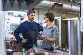 Male engineer and female manager doing inventory and talking in a factory