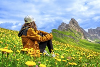 Female hiker enjoying the breathtaking view of the seceda mountain range in the dolomites, italy,