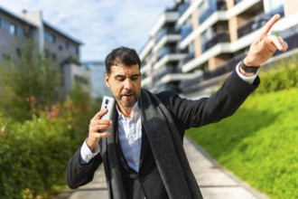Businessman enjoying day in the city dancing and celebrating while holding a smartphone
