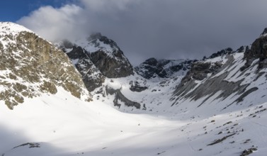 High mountain valley with mountain peak Piz Calderas in winter, view at the Chamanna Jenatsch in