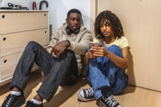 Two teenagers sitting on the floor of a cozy bedroom, using a smartphone and enjoying moments of