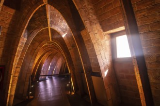 Warm sunlight streams through a window, illuminating the unique brick arches in the attic of casa