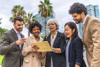 Mature businesswoman using digital tablet while talking with multi-ethic business colleagues during