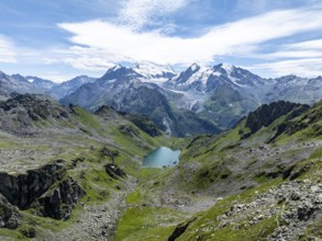 Mountain stream and mountain lake Lac de Louvie with glaciated summit of the Grand Combin, Val de