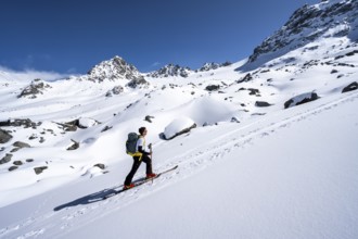 Ski tourers ascending through a picturesque snow-covered mountain landscape with peaks, ascent to