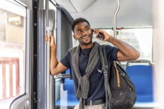 Young african businessman talking to the cellphone smiling and standing on the bus