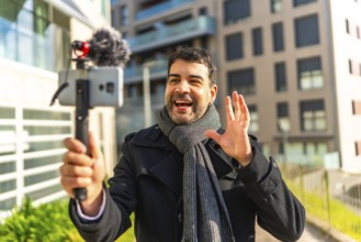 Male caucasian elegant mature vlogger waving while explaining something to the audience streaming