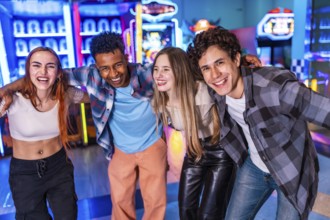 Four young cheerful multi ethnic friends are hugging each other, smiling and having fun together at