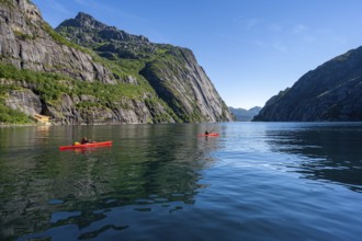 Two kayakers with red kayaks in the fjord Trollfjord, mountains reflected in the water, fjord