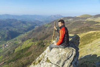 A man sitting on a rock at the top of Mount Ernio or Hernio in Gipuzkoa at sunset, Basque Country