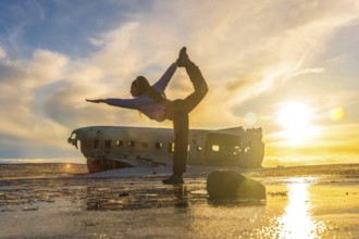 Woman on the Solheimasandur plane in Iceland performing a Natarajasana yoga pose to open the hip