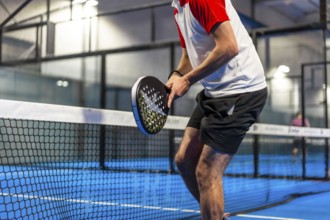 Cropped photo of an unrecognizable sportive man playing paddle tennis indoors