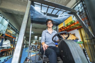 Frontal low angle view of a caucasian woman working in metallurgic factory driving a forklift