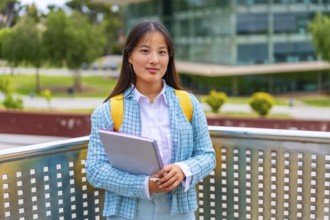 Three quarter length portrait of a beauty female asian student standing proud outside the