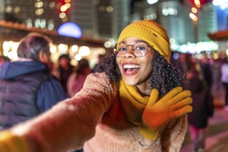 Cheerful young woman dressed in vibrant yellow winter clothes, capturing a joyful selfie amidst the