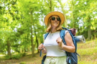 Smiling female backpacker day dreaming among greenery in the forest