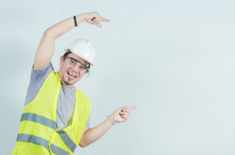 Happy young builder pointing an advertisement isolated. Smiling handsome engineer pointing to the