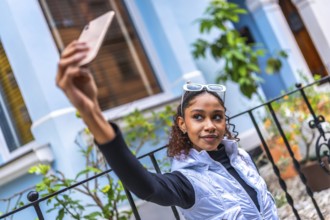 Urban stylish African american young woman taking selfie with cellphone in the city