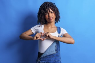 Studio portrait featuring a young woman forming a heart shape with her hands, radiating love and
