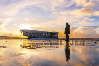 Young adventurous man at sunrise on Solheimasandur plane in winter in Iceland