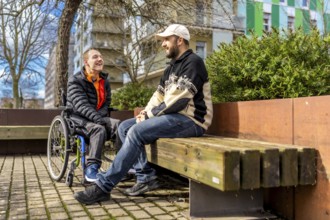 Two friends are enjoying a conversation in a city park, demonstrating inclusion and friendship