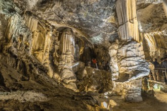 Tourists admiring giant stalactites and stalagmites inside the famous postojna cave, a major